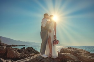 a man and woman kissing on a rocky beach